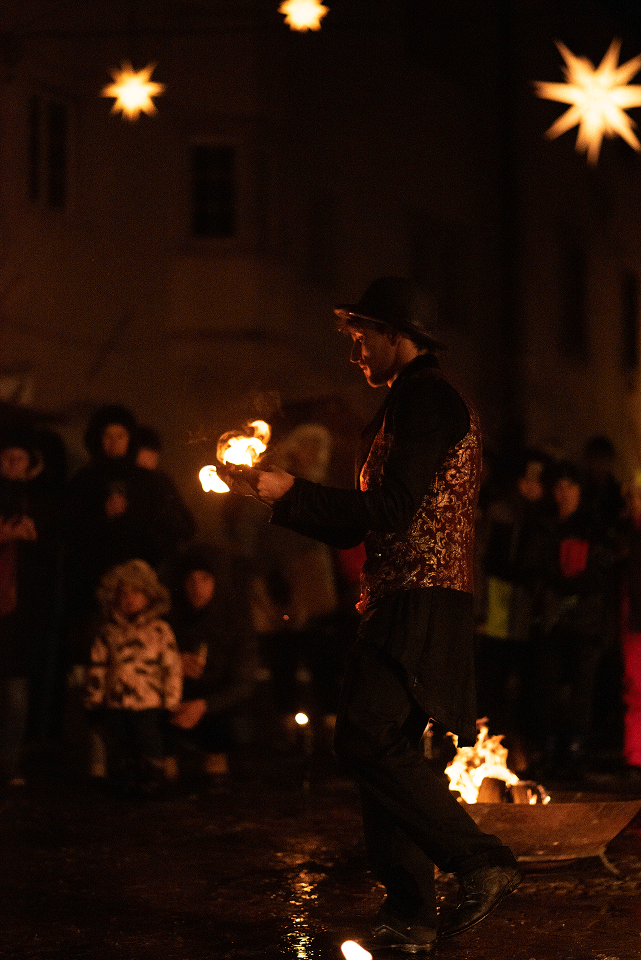 Traveller joungliert mit dem Feuer als der Zauber der Gesschichte. WEihnachts Show, Feuer Show, Dorfplatz, Südtirol Winterliche Feuershow mit Elfen, Flammen und festlicher Musik für Kinder